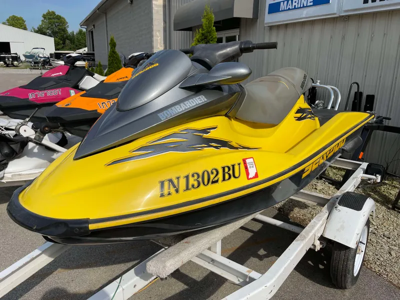 Slide: The Image of Yellow 2002 Sea-Doo RX jet ski on trailer, parked outside a marine shop. - 2