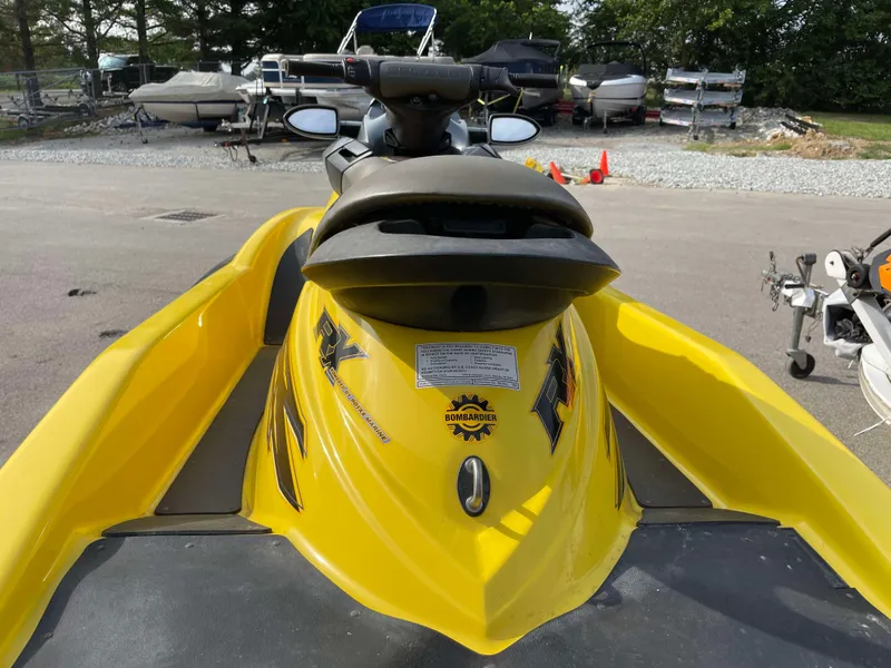 Slide: The Image of 2002 Sea-Doo RX jet ski, yellow, parked outdoors with other boats in the background. - 4