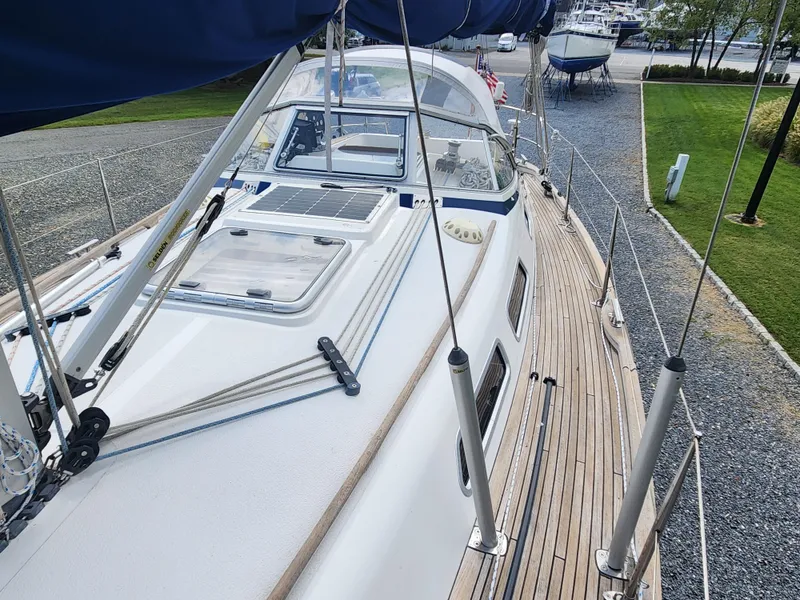 Slide: The Image of 2016 Hallberg-Rassy 342 sailboat with teak deck and blue canvas, docked in a marina. - 14
