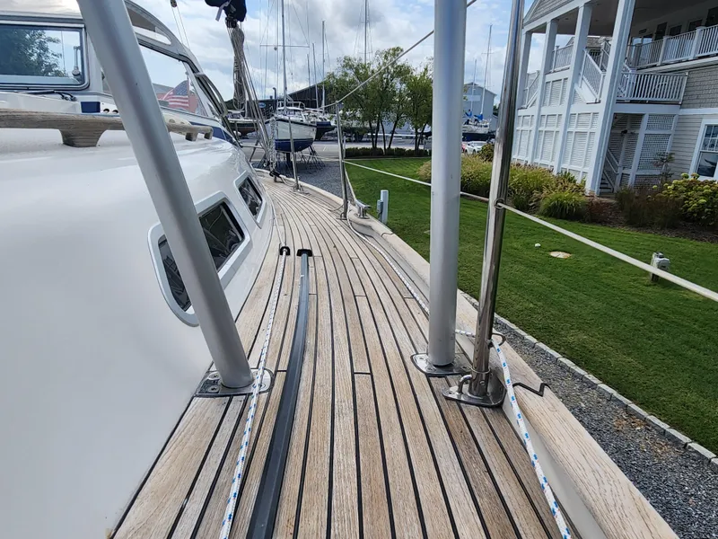 Slide: The Image of Deck view of 2016 Hallberg-Rassy 342 sailboat, showcasing teak wood and marina background. - 16