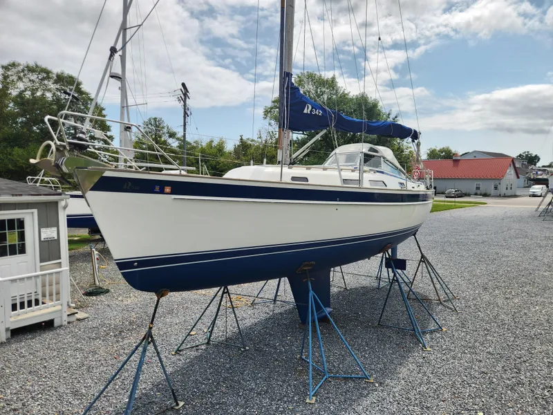 Slide: The Image of 2016 Hallberg-Rassy 342 sailboat on stands in a boatyard under a partly cloudy sky. - 2