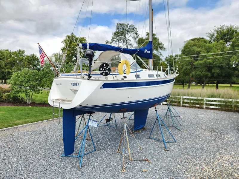 Slide: The Image of 2016 Hallberg-Rassy 342 sailboat on stands, outdoors, with trees and cloudy sky. - 3