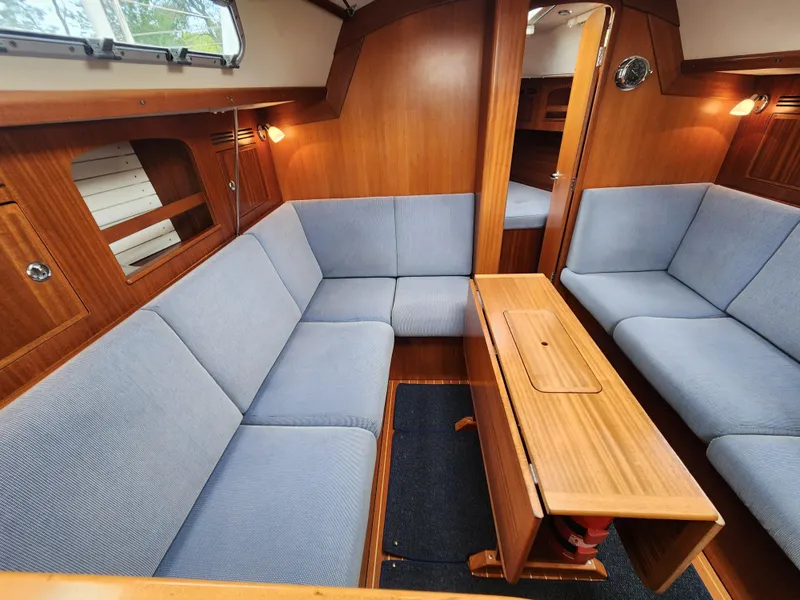Slide: The Image of 2016 Hallberg-Rassy 342 yacht interior with blue seating and wooden table. - 32