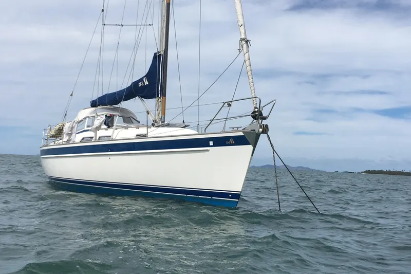 Slide: The Image of 2016 Hallberg-Rassy 342 sailboat anchored on calm sea under a cloudy sky. - 7