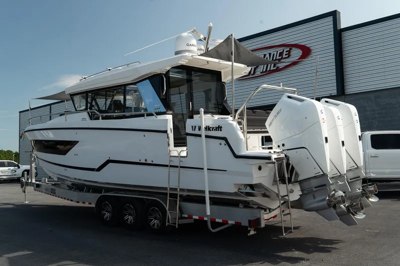 Slide: The Image of 2025 Wellcraft 355 boat on trailer, triple outboard engines, parked outdoors. - 3