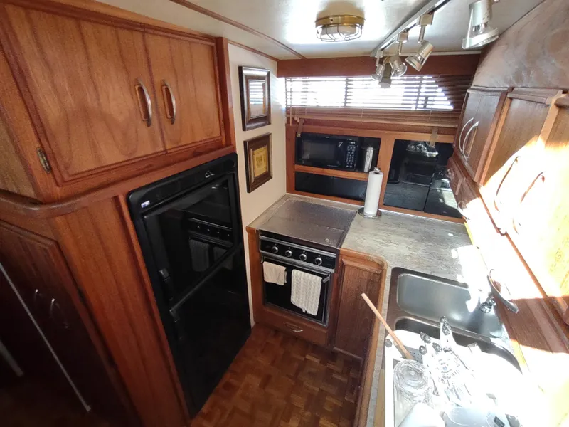 Slide: The Image of 1988 Marinette Marquis Motor Yacht kitchen with wood cabinetry, oven, and sink. - 19