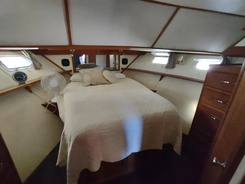 Slide: The Image of 1988 Marinette Marquis Motor Yacht bedroom with cozy bed, wooden accents, and natural light. - 20