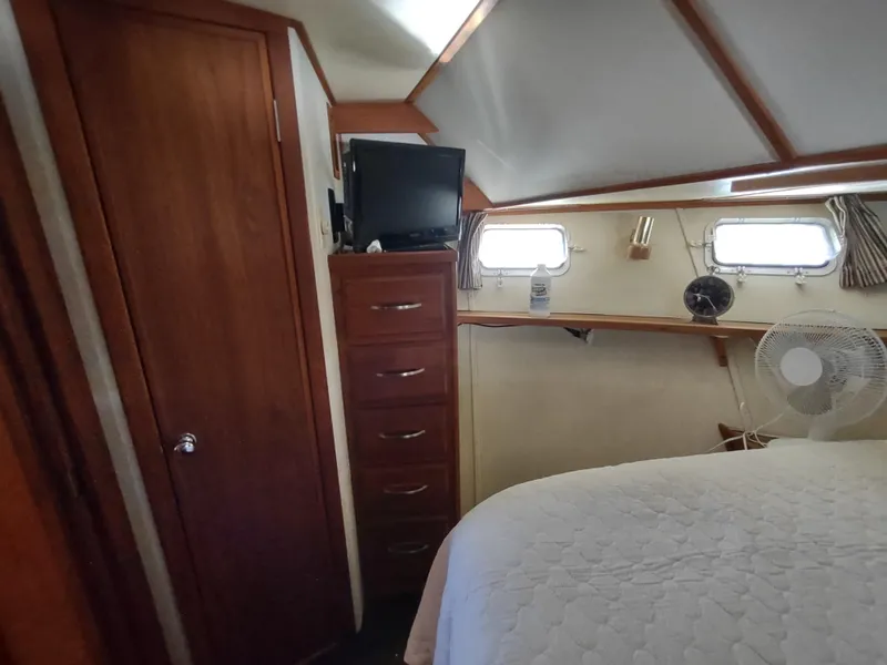 Slide: The Image of 1988 Marinette Marquis Motor Yacht cabin with bed, drawers, TV, and windows. - 21