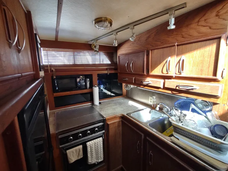 Slide: The Image of 1988 Marinette Marquis Motor Yacht kitchen with wooden cabinets, stove, and sink. - 24
