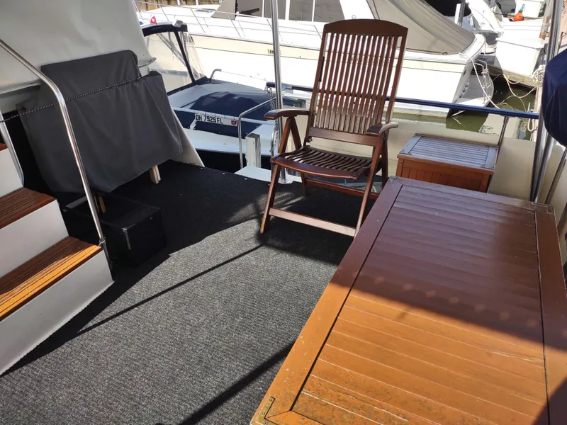 Slide: The Image of 1988 Marinette Marquis Motor Yacht deck with wooden chair and table, docked at marina. - 6