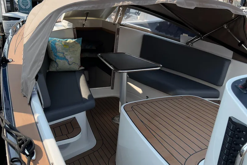 Slide: The Image of 2022 AdmiralsTender C28 boat interior with seating and table, featuring wood flooring and canopy. - 13