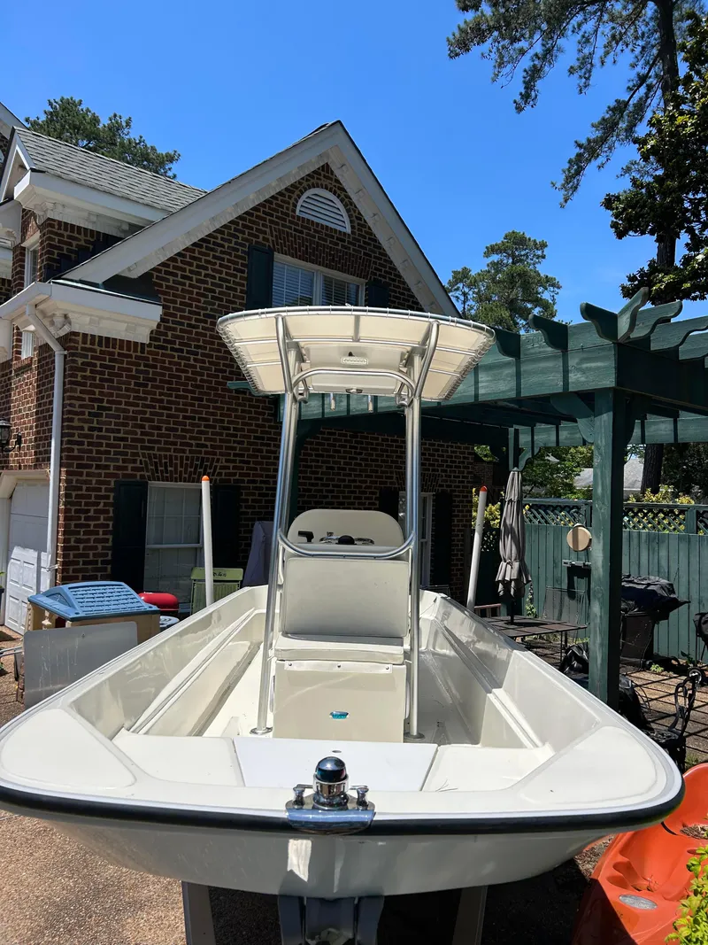 Slide: The Image of 2022 Boston Whaler 17 Montauk boat parked near a brick house under a clear blue sky. - 8