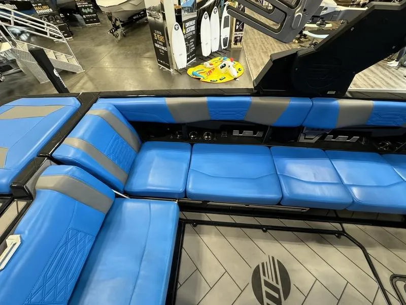 Slide: The Image of 2022 Malibu 25 LSV boat interior with blue and gray seating, showroom display. - 11