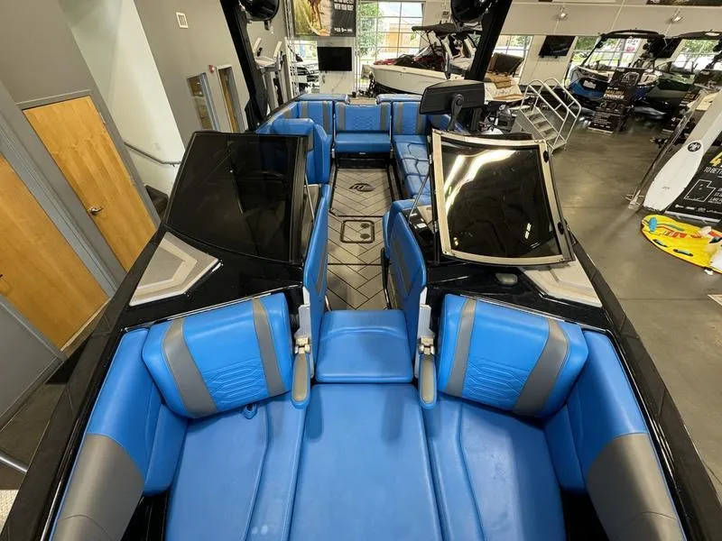 Slide: The Image of 2022 Malibu 25 LSV boat interior with blue and gray seating in showroom. - 16