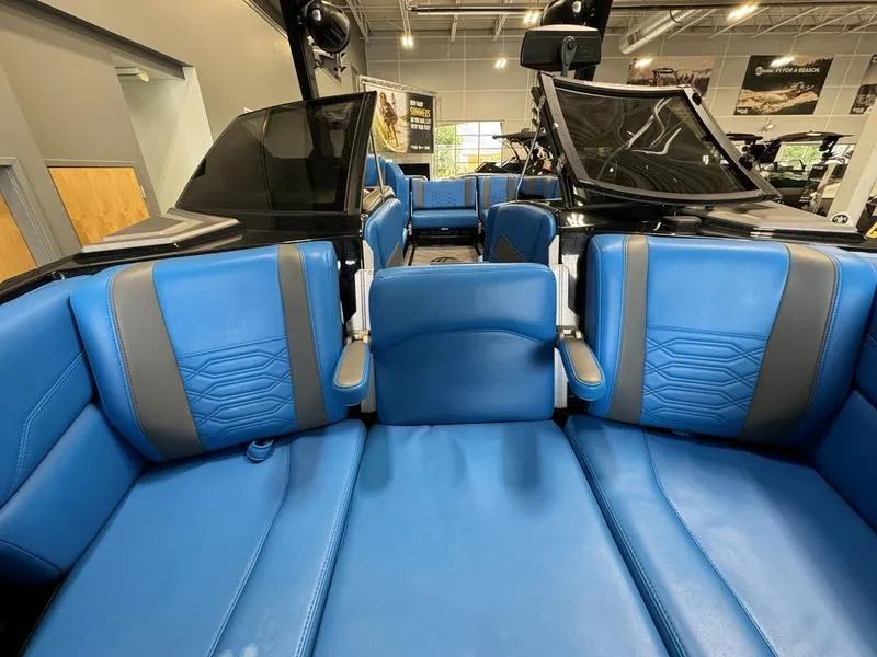 Slide: The Image of 2022 Malibu 25 LSV boat interior with blue and gray seating in showroom. - 22
