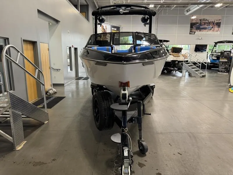 Slide: The Image of 2022 Malibu 25 LSV boat displayed indoors on a trailer. - 4