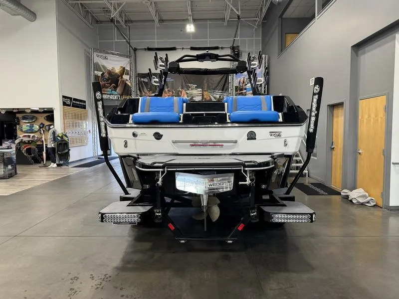 Slide: The Image of 2022 Malibu 25 LSV boat in showroom, rear view with blue seating. - 5