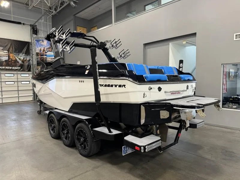 Slide: The Image of 2022 Malibu 25 LSV boat in showroom, featuring sleek design and blue seating. - 6