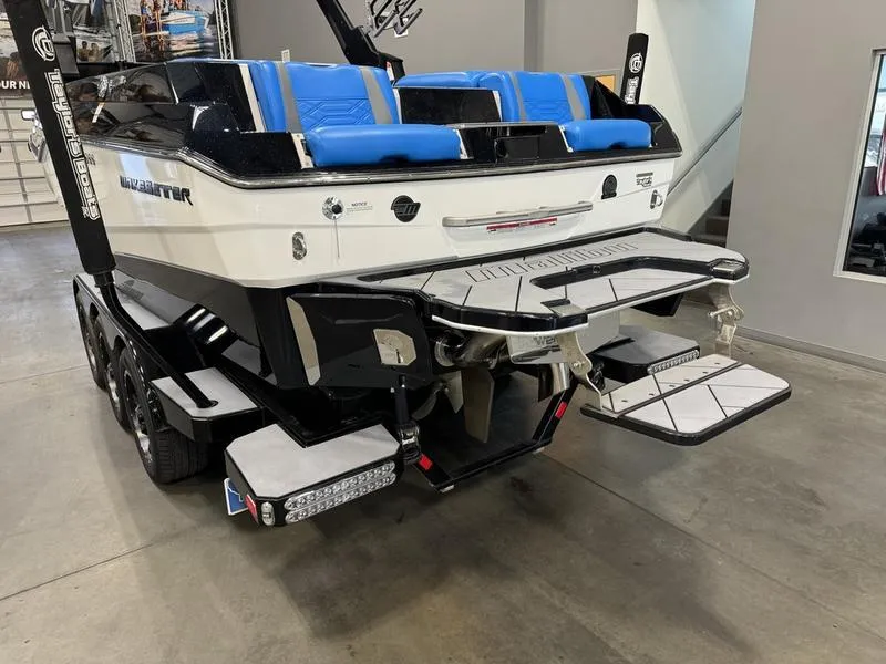 Slide: The Image of 2022 Malibu 25 LSV boat with blue seating and sleek design in showroom. - 7