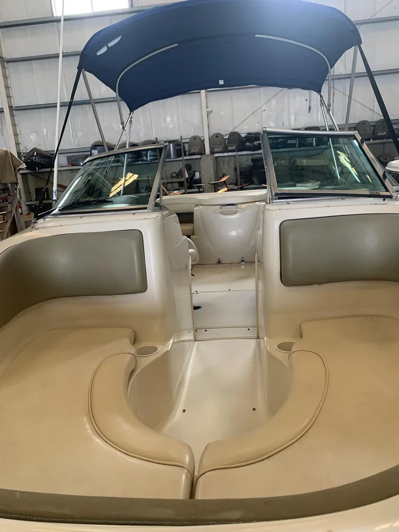 Slide: The Image of 2004 Sea Ray 200 Sport boat interior with seating and blue canopy in a storage facility. - 13