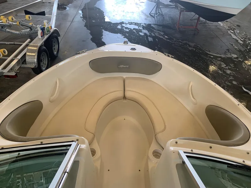Slide: The Image of 2004 Sea Ray 200 Sport boat interior with beige seating in a garage setting. - 9