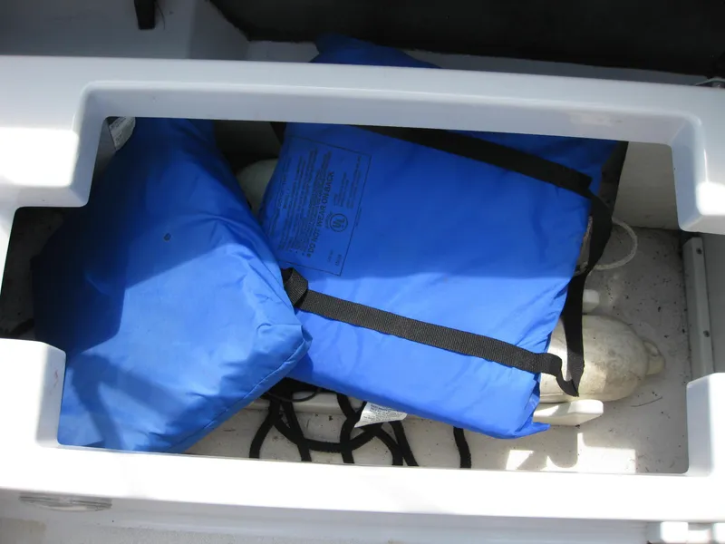 Slide: The Image of Blue life jackets stored in a 2000 Four Winns 235 Sundowner I/O boat compartment. - 17