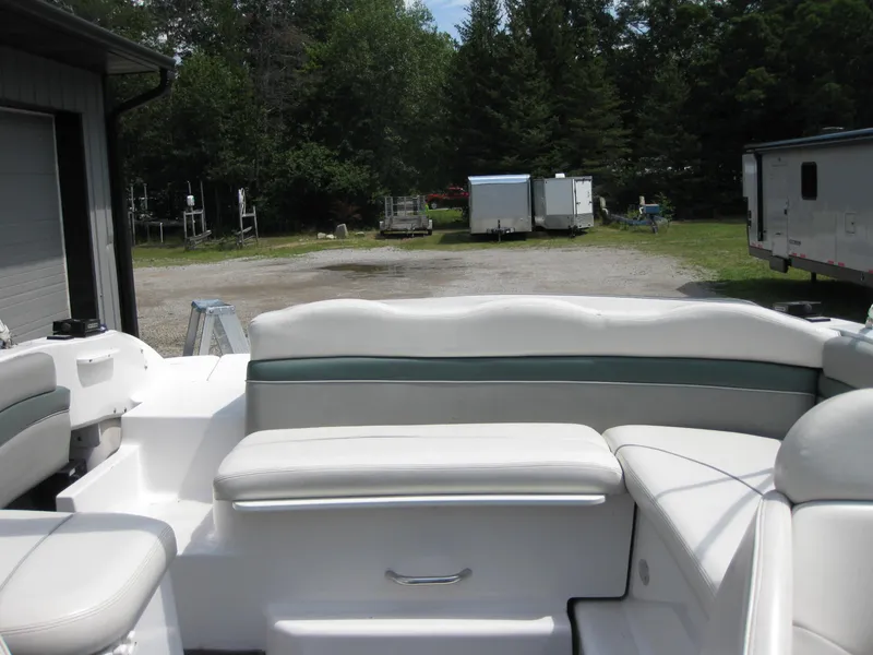 Slide: The Image of 2000 Four Winns 235 Sundowner I/O boat interior with white seating, parked outdoors. - 9