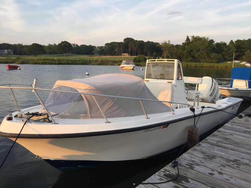 Slide: The Image of 1986 Mako 231 CC boat docked by a serene lake. - 10