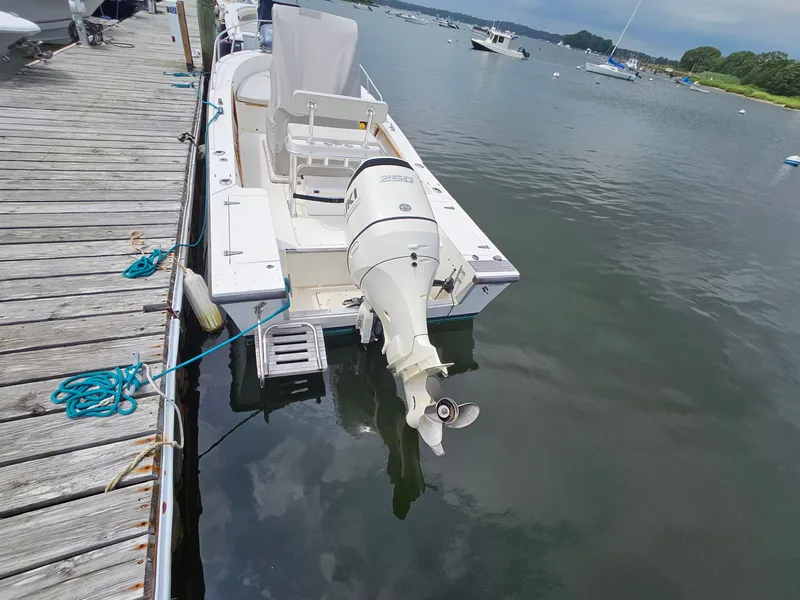 Slide: The Image of 1986 Mako 231 CC boat docked by a wooden pier on a calm lake. - 3