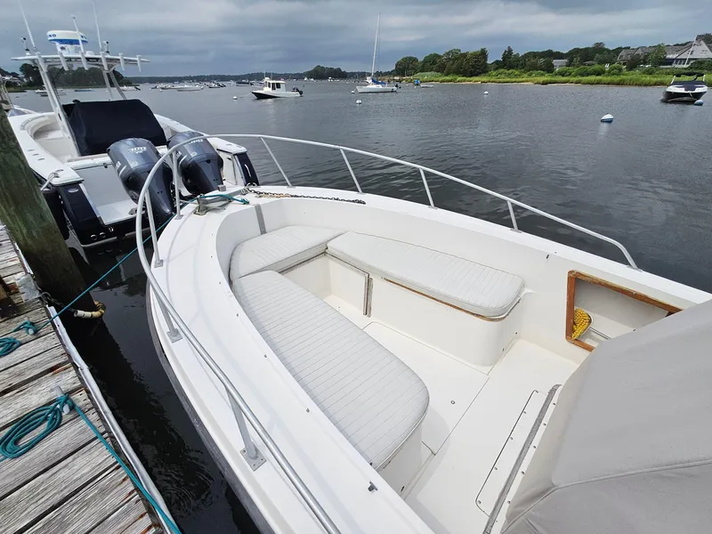 Slide: The Image of 1986 Mako 231 CC boat docked by the water, featuring spacious seating. - 4