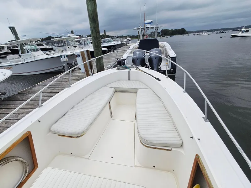 Slide: The Image of 1986 Mako 231 CC boat docked, featuring spacious seating and twin engines. - 5