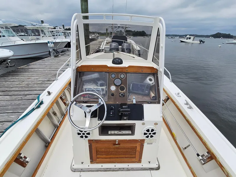 Slide: The Image of 1986 Mako 231 CC boat dashboard at marina, featuring steering wheel and gauges. - 7