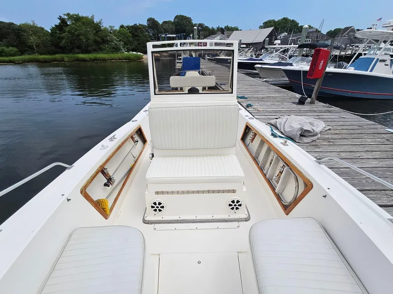 Slide: The Image of 1986 Mako 231 CC boat interior at dock, featuring white seating and console. - 8