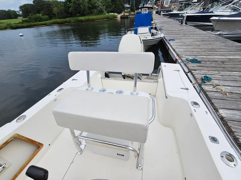 Slide: The Image of 1986 Mako 231 CC boat docked, featuring white seating and a calm waterfront setting. - 9