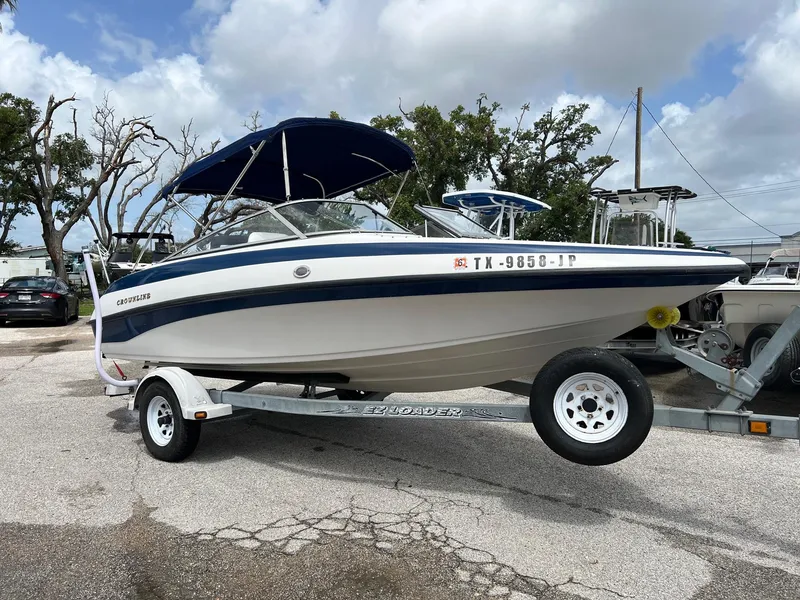 The Image of 2002 Crownline 180 BR boat on trailer with blue canopy, parked outdoors. - 0