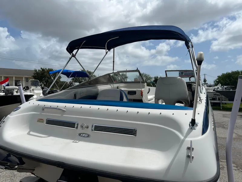 Slide: The Image of 2002 Crownline 180 BR boat with blue canopy, parked outdoors under cloudy sky. - 3
