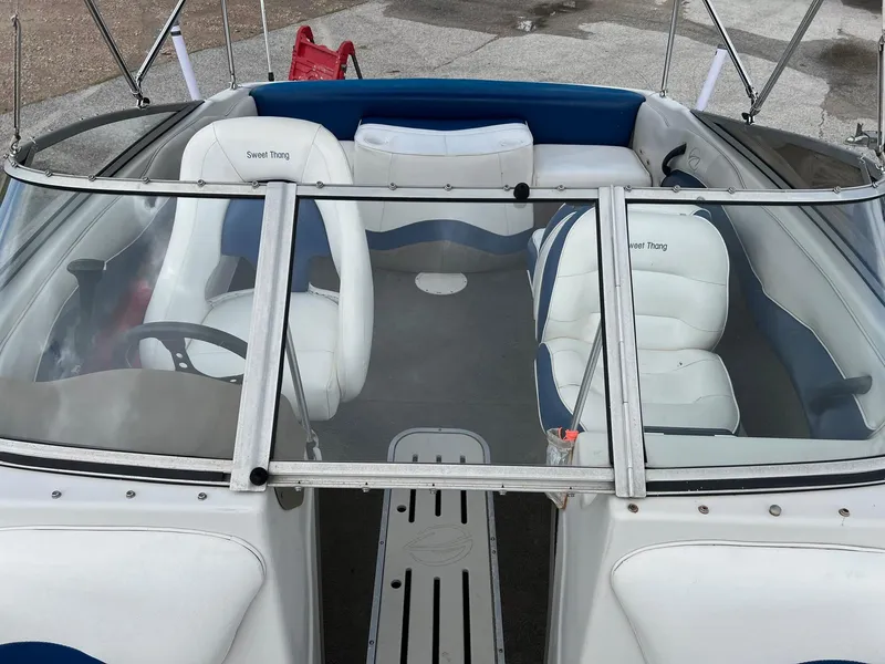 Slide: The Image of 2002 Crownline 180 BR boat interior with white and blue seating, open windshield, and steering wheel. - 9