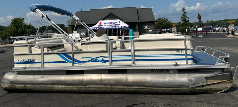 The Image of 1998 Crest II pontoon boat with blue accents, parked outdoors. - 0