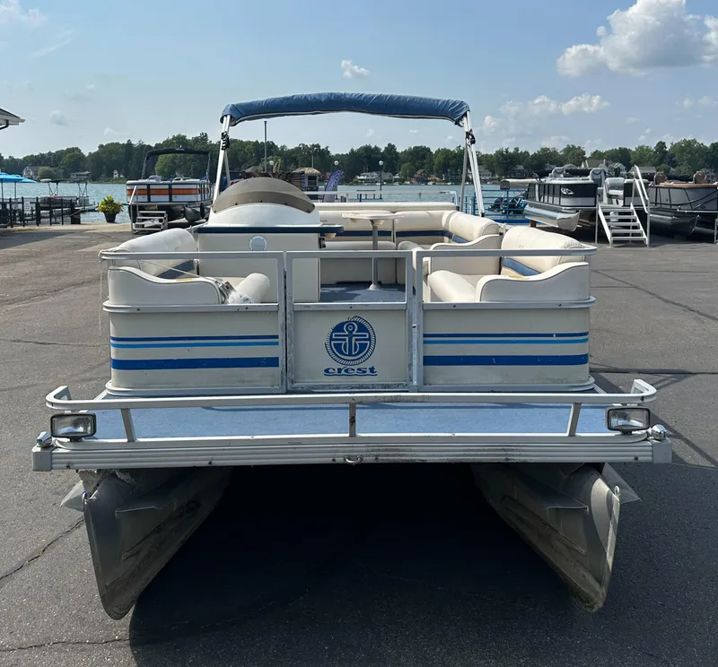 Slide: The Image of 1998 Crest II pontoon boat docked at a marina under a clear sky. - 2