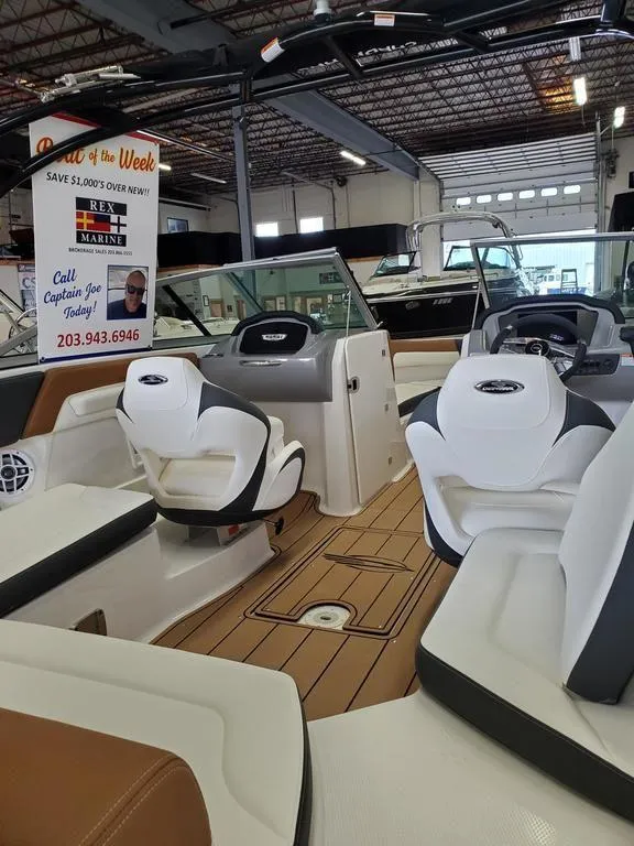 Slide: The Image of 2024 Chaparral 23 SSi OB boat interior with seating and dashboard in a showroom. - 4