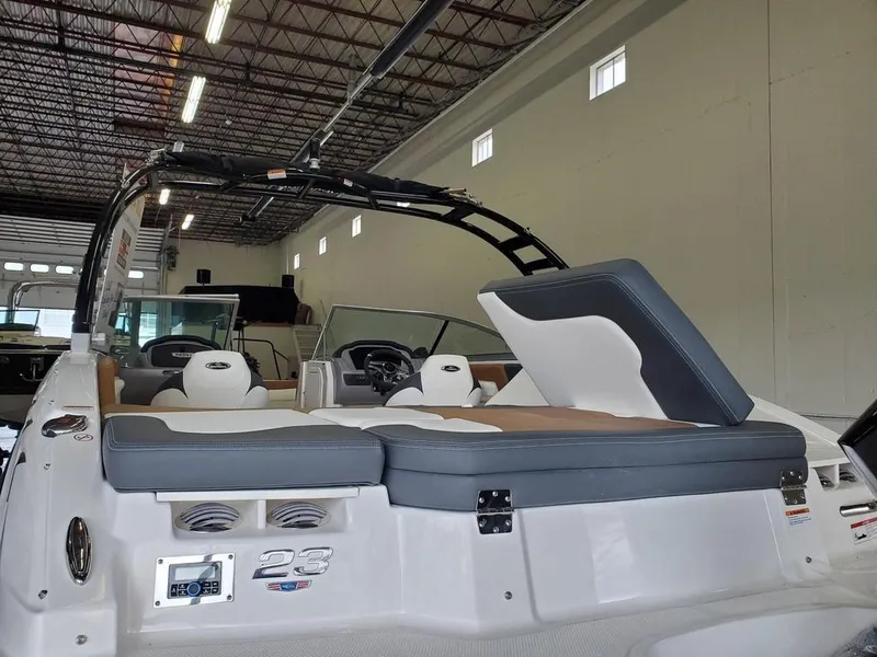 Slide: The Image of 2024 Chaparral 23 SSi OB boat interior with seating and dashboard in a showroom. - 5