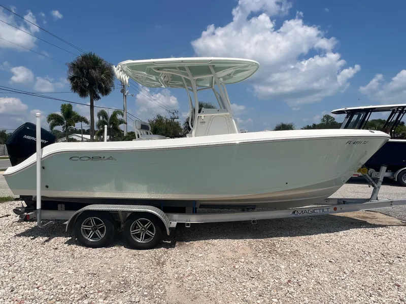 Slide: The Image of 2023 Cobia 237 CC boat on trailer under blue sky. - 0
