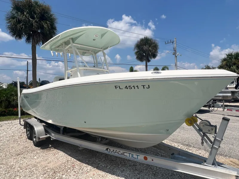 Slide: The Image of 2023 Cobia 237 CC boat on trailer, parked outdoors under a clear blue sky. - 1