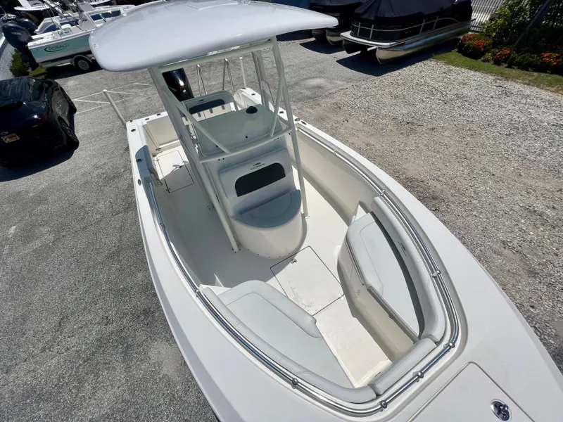 Slide: The Image of 2023 Cobia 237 CC boat, white interior, center console, parked on gravel lot. - 15