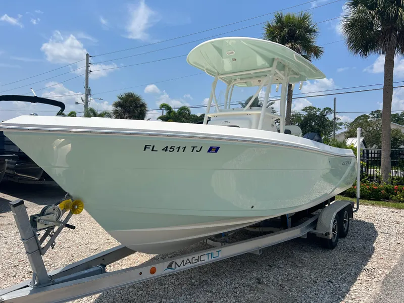Slide: The Image of 2023 Cobia 237 CC boat on trailer, sunny day, palm trees in background. - 3