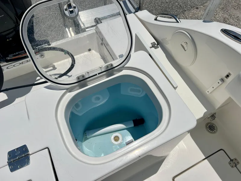 Slide: The Image of 2023 Cobia 237 CC boat livewell with open lid, showcasing interior features. - 9