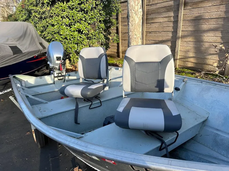 Slide: The Image of 1983 Valco 12 boat with two cushioned seats and an outboard motor, parked outdoors. - 10