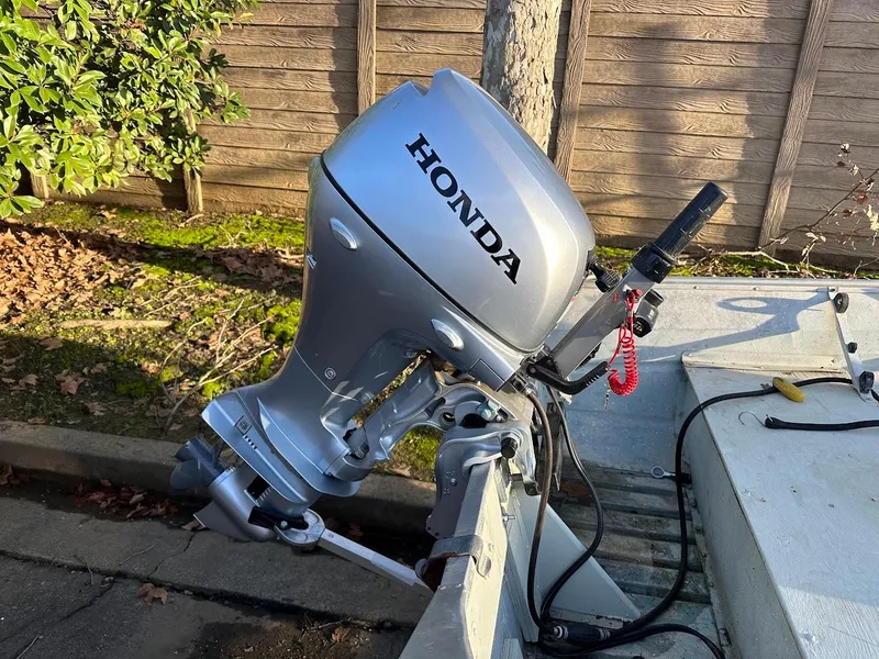 Slide: The Image of Silver Honda outboard motor on a 1983 Valco 12 boat, parked outdoors. - 6
