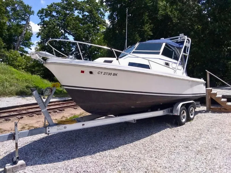 Slide: The Image of 1987 Hinterhoeller Limestone Express boat on trailer, parked outdoors on gravel. - 1