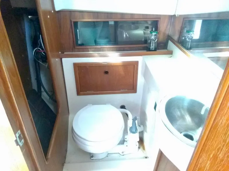 Slide: The Image of 1987 Hinterhoeller Limestone Express boat bathroom with toilet, sink, and wooden cabinetry. - 14